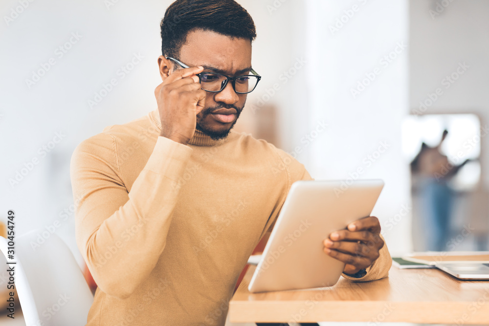 Poster serious afro manager using his touchpad to read email