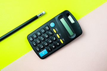 Pencil and calculator on yellow and pink  background.