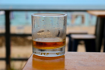 Whiskey or scotch almost empty glass on table outside