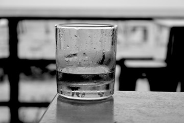 Whiskey or scotch almost empty glass on table outside black and white