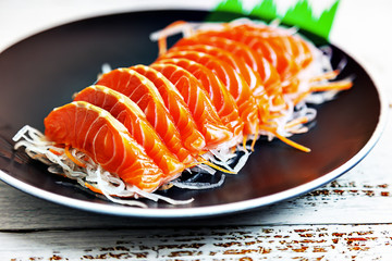 Sliced ​​salmon fillets in a black dish, ready to be eaten.