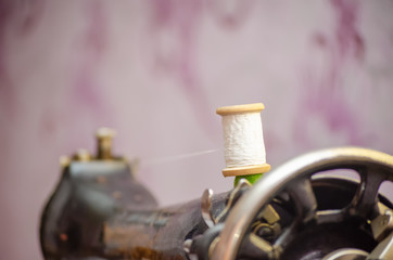 Close up of a spool of white thread on a sewing machine