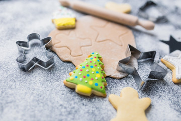 Making Christmas cookies concept made of sugar, cutters, dough, rolling pin and biscuits with colorful icing on table.