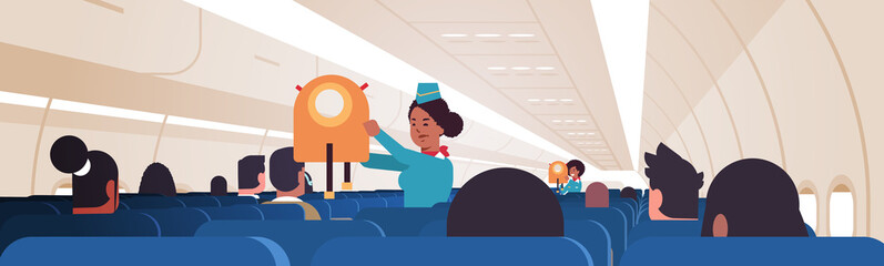 stewardess explaining for passengers how to use jacket life vest in emergency situation african american flight attendants safety demonstration concept modern airplane board interior horizontal vector