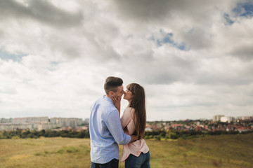 Young couple outdoor portrait. Beautiful pretty girl kissing handsome boy. Sensual photo.