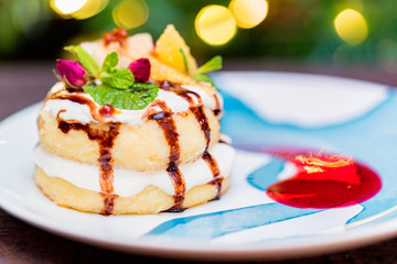 Cottage cheese pancakes or syrniki with cream, fruit jam and flower decoration