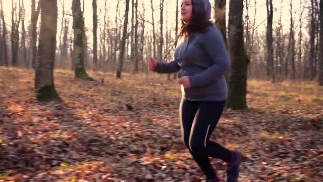 Motivated fat girl runs through forest to fight overweight.Slow motion.