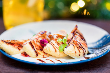 Cottage cheese pancakes or syrniki with cream, fruit jam and flower decoration