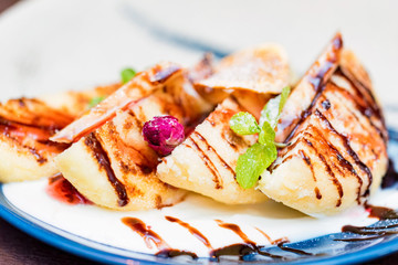 Cottage cheese pancakes or syrniki with cream, fruit jam and flower decoration