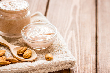Fototapeta na wymiar body scrub with almonds for body care on wooden table background