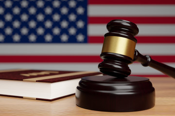 Judge's hammer and book of law on a wooden surface on the background of the flag of the United States of America.3D render.