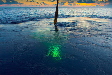 Cable lowering submersible in ocean at sunset