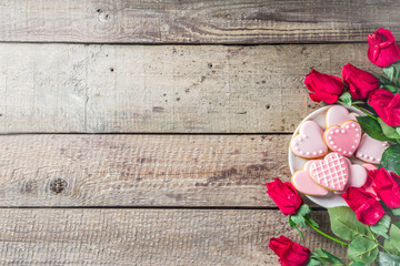 Valentine day greeting background with red rose flowers and pink glazed heart shaped cookies