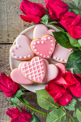 Obraz na płótnie Canvas Valentine day greeting background with red rose flowers and pink glazed heart shaped cookies