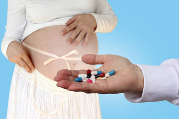 doctor, nurse, pharmacist in white uniform holds out to a pregnant girl a handful of multi-colored pills, pharmacological concept, medical
