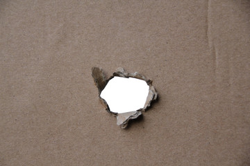 empty blank cardboard form, craft paper, hole with roughly torn edge, concept of secrecy, tracking, spying, blank for the designer, close-up, copy space