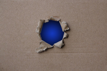 Classic Blue empty blank cardboard form, craft paper, hole with roughly torn edge, concept of secrecy, tracking, spying, blank for the designer, close-up, copy space