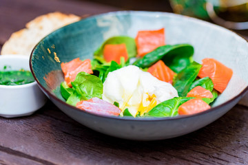 Bowl with salmon salad with poached egg, bread and sauce