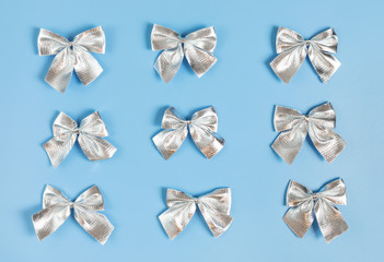 Christmas pattern with silver bows on pastel blue background.