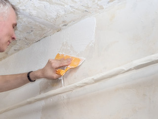 Worker hands holding a spatula with white putty. Repair and renovation at home. New interior design. 