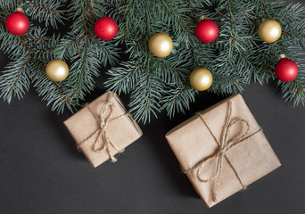 Christmas composition with fir branches, red and gold balls and gifts on a black background.