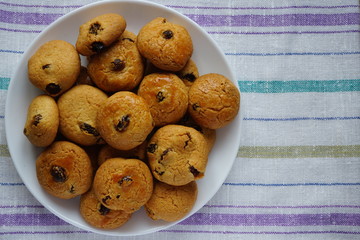 Closeup of fresh baked homemade raisin cookies in a white plate with copy space
