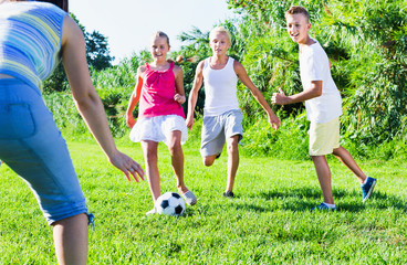 Obraz premium Three happy kids playing with ball outdoors, running together