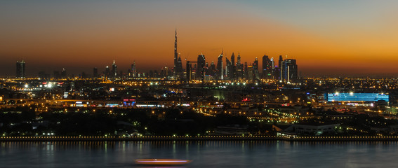 Dubai susnet over the creek in the background the silhouette of the tall buildings 