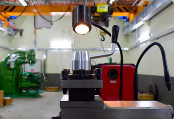 Closeup of metallic lathe working against factory industrial interior background, nobody