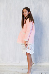 Fototapeta premium Portrait of a beautiful fashionable girl in a pink jacket and white dress