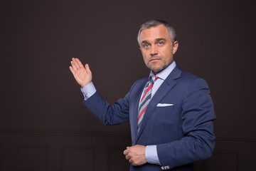 A portrait of a man on a matte brown wall in the background. A businessman.