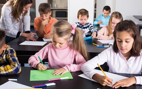 calm little children with teacher drawing in classroom