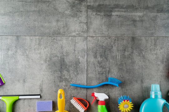 House Cleaning Concept. Top View Of Colorful Cleaning Products On Gray Tile Floor.