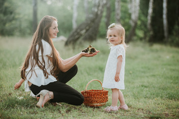 Mother shows children little ducklings in wicker basket. duckling in the hands of a woman. mom shows her daughter a little duckling in the park