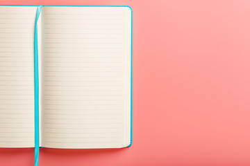 Open a laptop with blank pages on a pink background. Top view, copy space