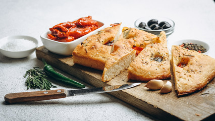 Traditional Italian Focaccia with tomatoes, olives and rosemary - homemade flat bread focaccia.