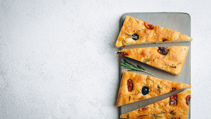 Traditional Italian Focaccia with tomatoes, olives and rosemary - homemade flat bread focaccia.