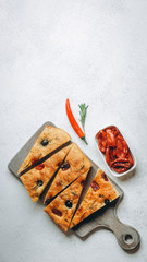 Traditional Italian Focaccia with tomatoes, olives and rosemary - homemade flat bread focaccia.