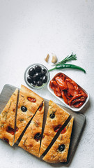 Traditional Italian Focaccia with tomatoes, olives and rosemary - homemade flat bread focaccia.