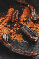 Carob fruit on a black textured background in the shape of an exploding flower.