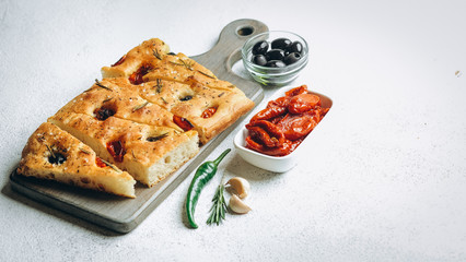 Traditional Italian Focaccia with tomatoes, olives and rosemary - homemade flat bread focaccia.