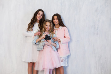 Portrait of three beautiful fashionable girlfriend girls with a photo shoot camera