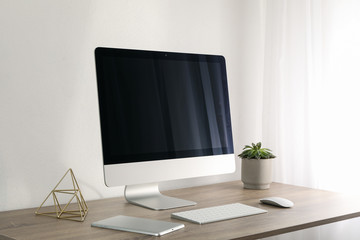 Workplace with computer and plant on wooden table. White background