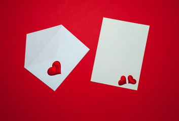 The Concept Of Valentine's Day. Love letter. An envelope, a blank sheet of paper, red hearts on a red background. Free space for your text.