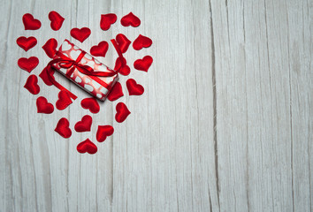 The concept of Valentine's day. Gift box and red hearts on a light wooden background. Free space for your text.