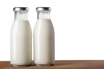 Two bottles of milk on a wooden table isolated on white.