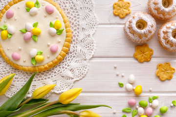 Fototapeta na wymiar Easter background with marzipan eggs, mazurek pastry, spring flowers on white wooden background, top view, copy space