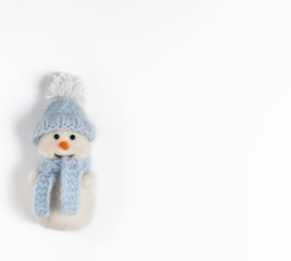 Cute funny snowman in blue hat and scarf on white background. Christmas wool toy.