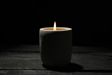 Fototapeta na wymiar Candle on wooden table against black background, close up