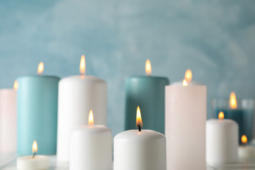 Different burning candles against blue background, space for text
